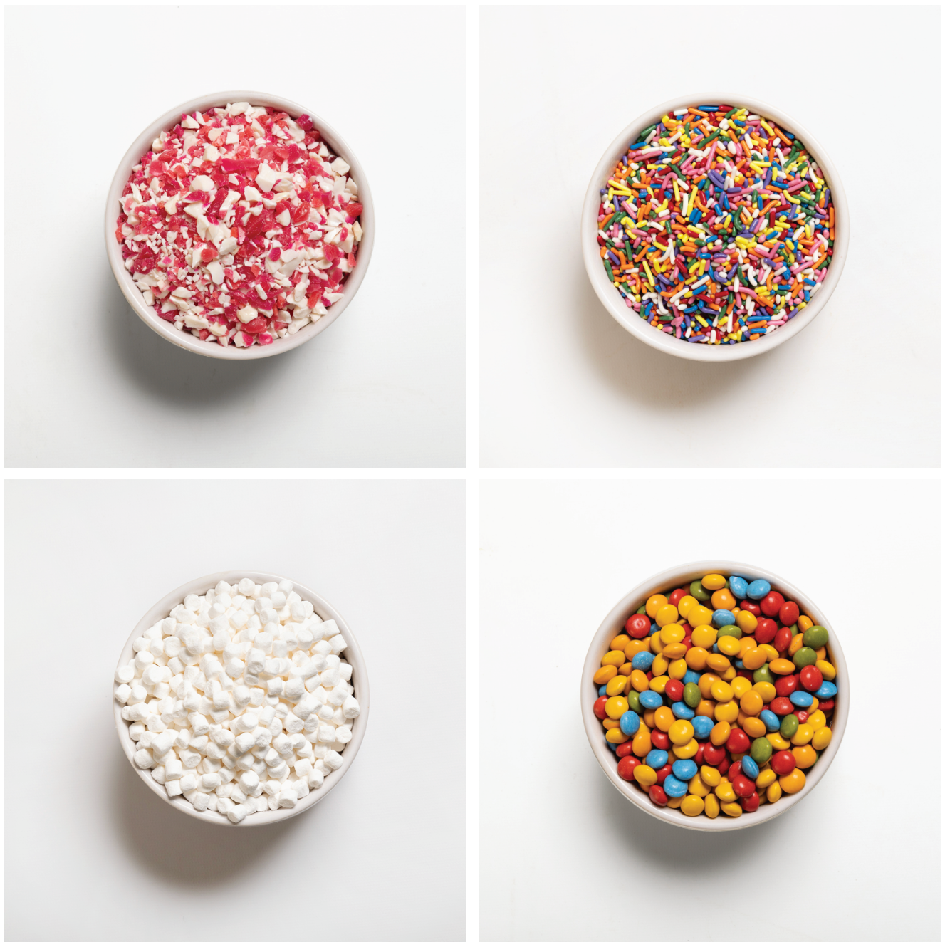 Four bowls with different types of colorful toppings on a white background
