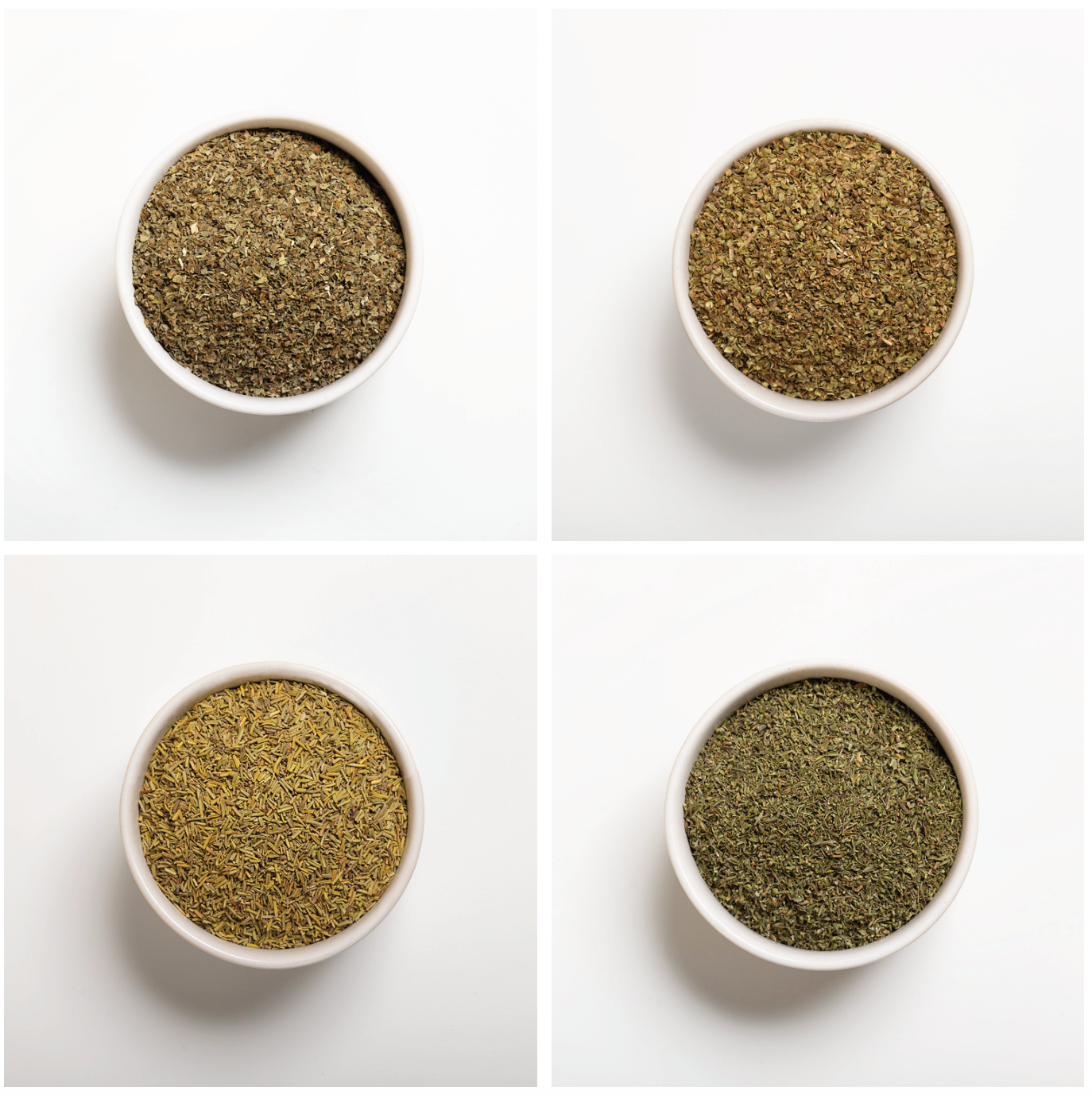 Four white bowls filled with different types of dried green herbs on a white background