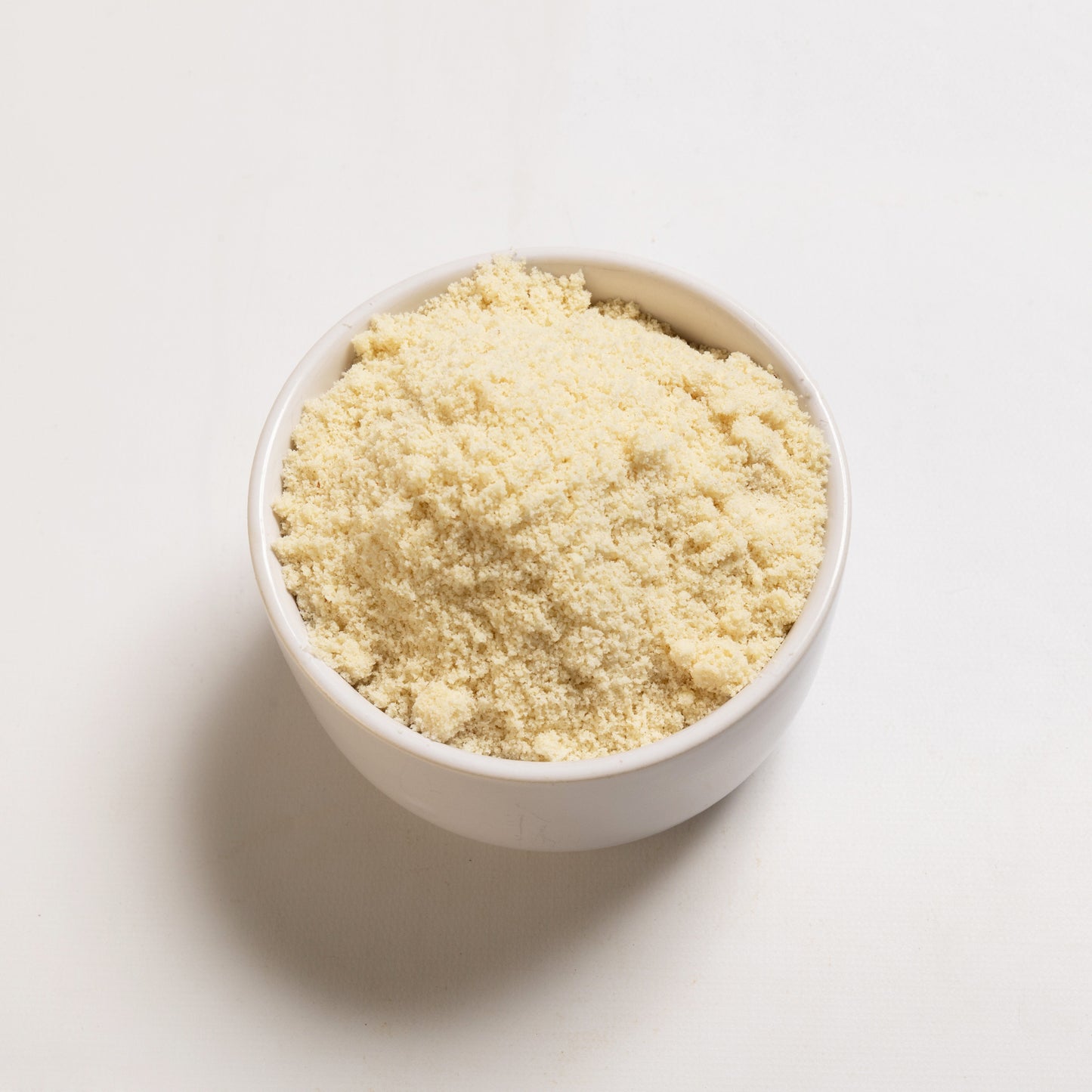 A bowl filled with blanched almond meal on a white background 