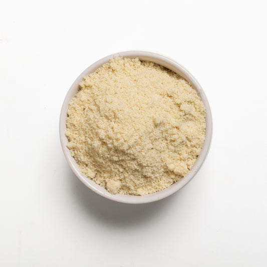 A bowl filled with blanched almond meal on a white background