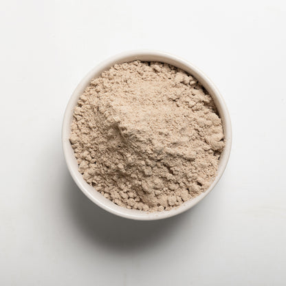 A bowl filled with brown teff flour on a white background 