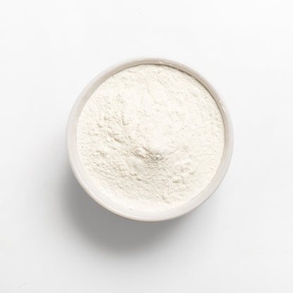 A bowl of white cassava flour on a white background.