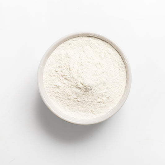 A bowl of white cassava flour on a white background.