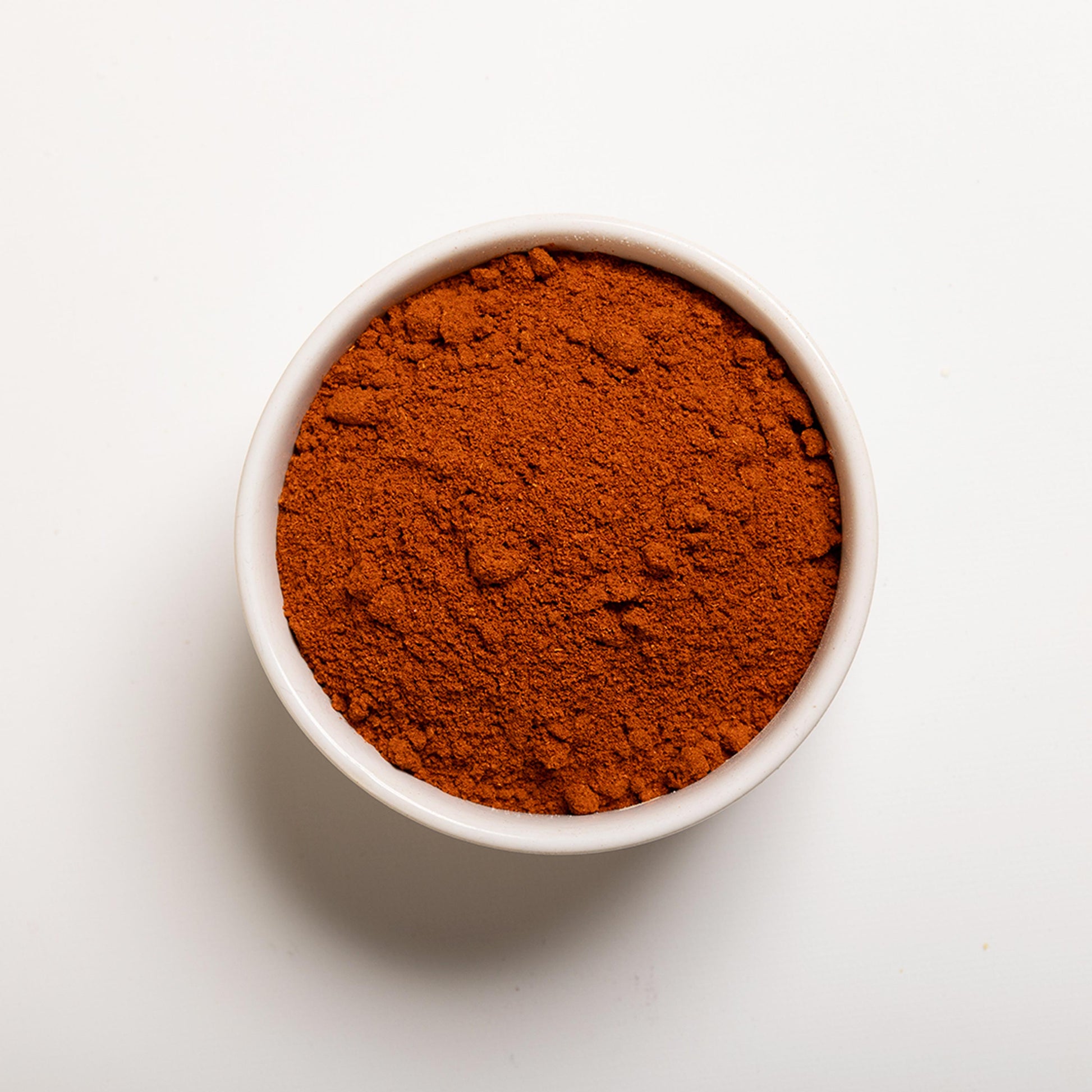 White bowl filled with Cayenne Pepper powder on a white background 