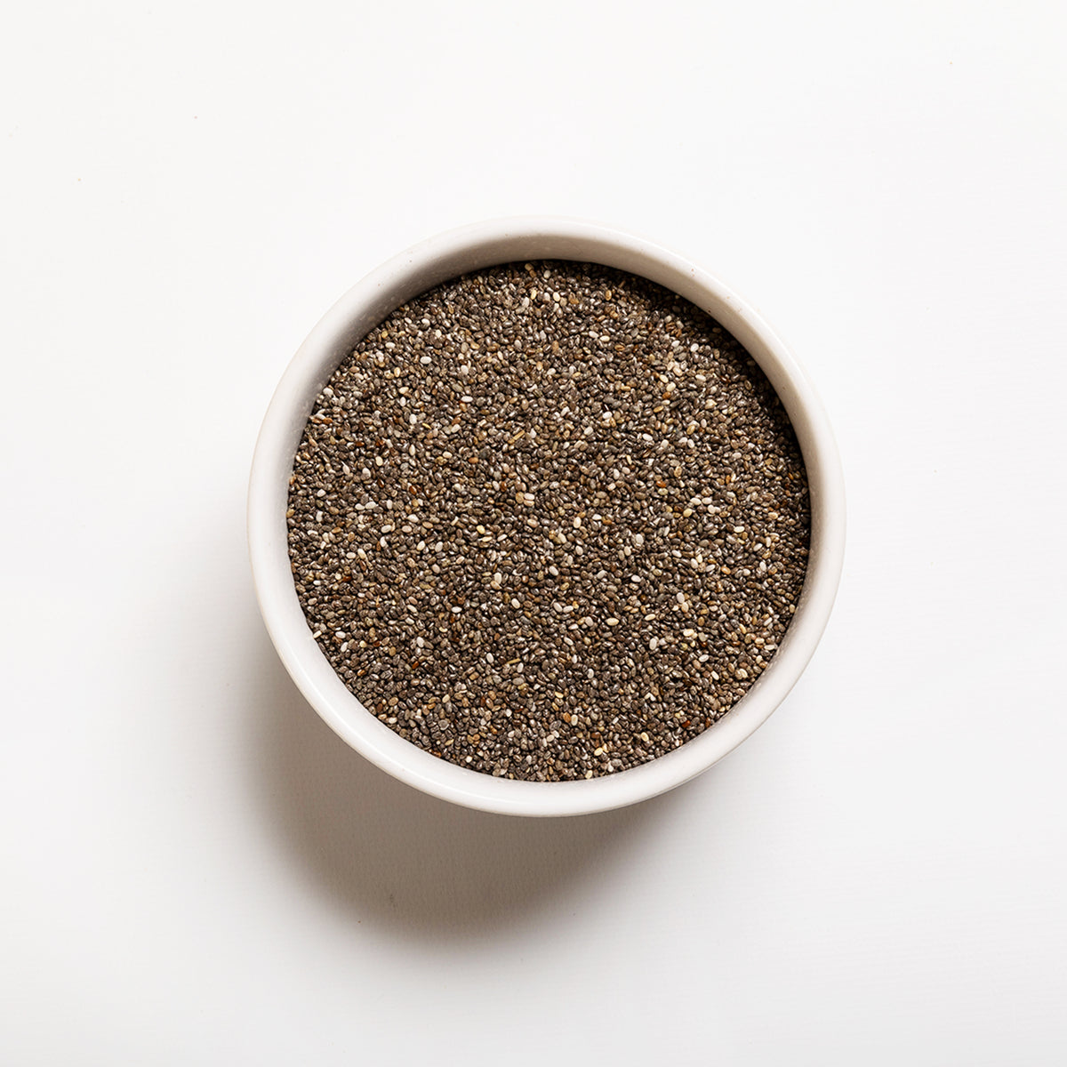 White bowl filled with chia seeds on a white background