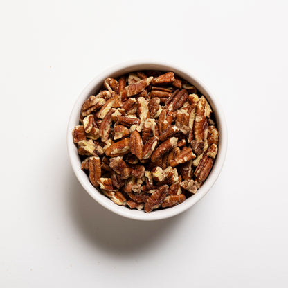 A bowl filled with chopped pecans on a white background