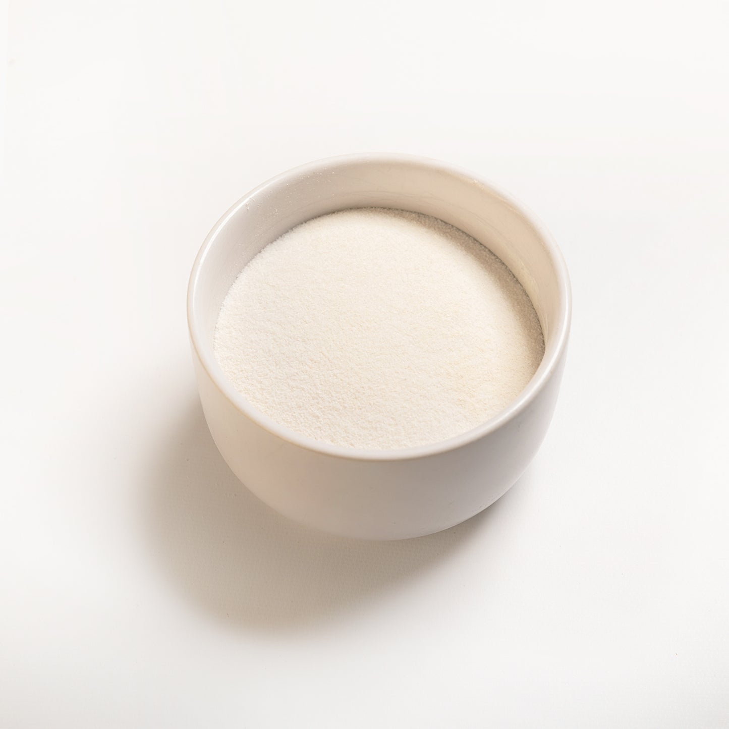 A small white bowl containing finely powdered citrus pectin 