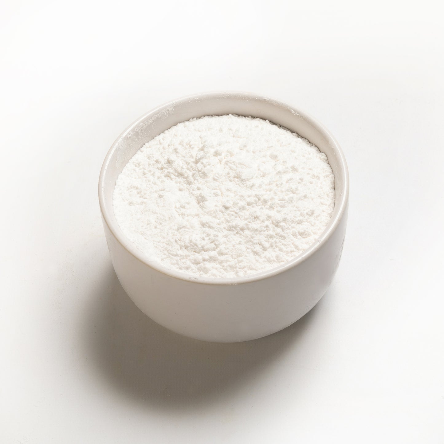 A bowl filled with cream of tartar on a white background.