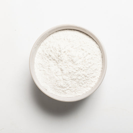 A bowl filled with cream of tartar on a white background.