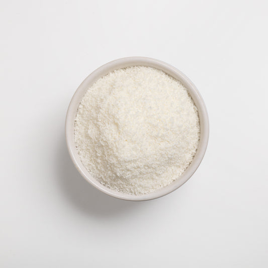 A bowl of finely shredded desiccated coconut on a white background.