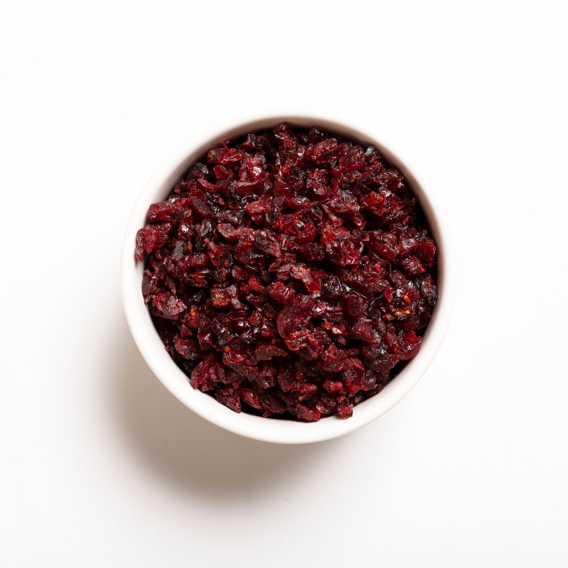 A white bowl filled with julienne cut, sweetened dried cranberries on a white background.