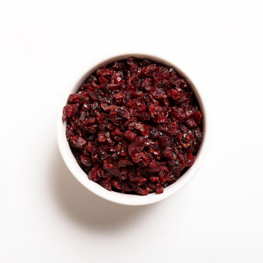 A white bowl filled with julienne cut, sweetened dried cranberries on a white background.