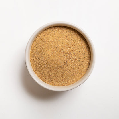 A bowl filled with drum dried sweet potato flakes on a white background.