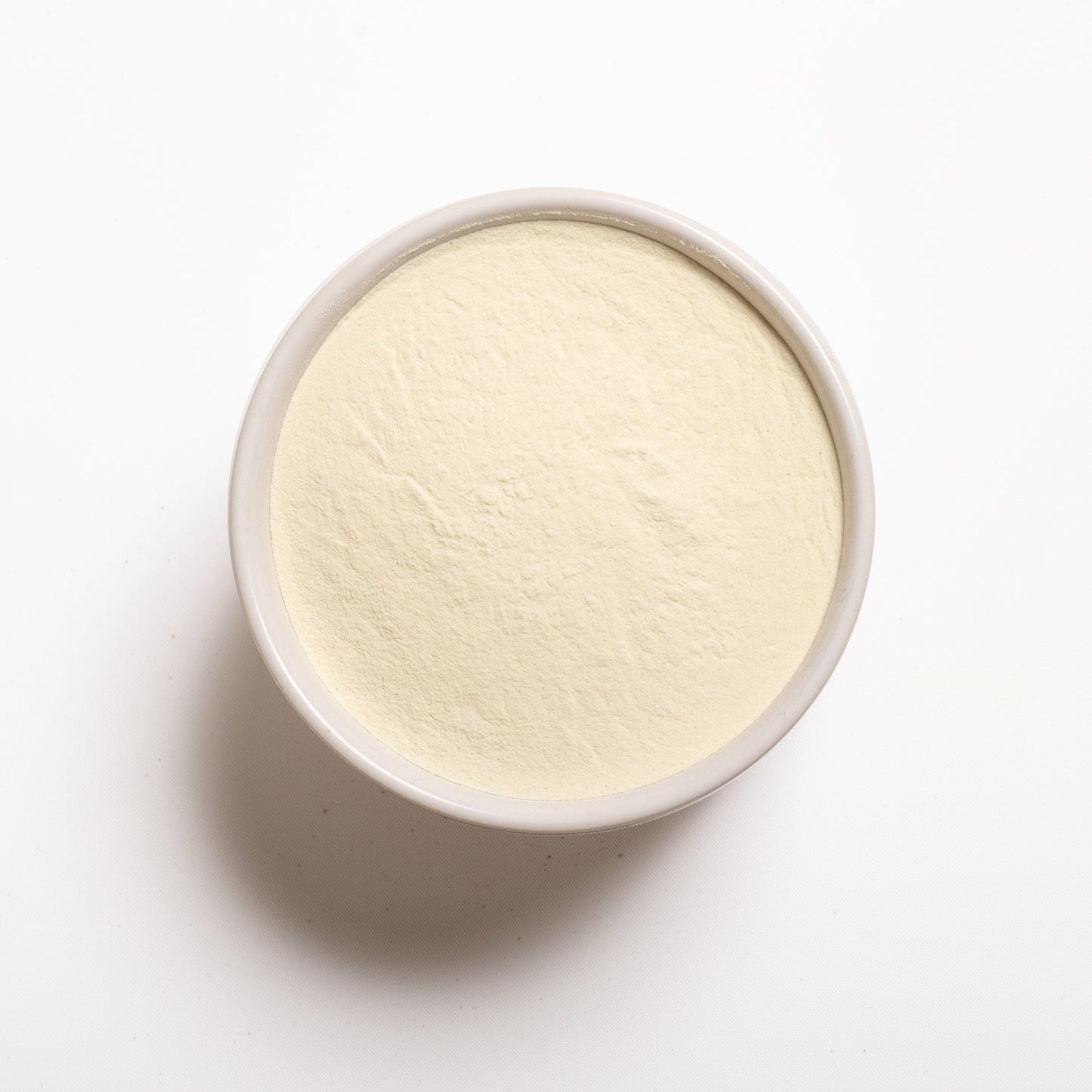 A bowl filled with potato flour on a white background.