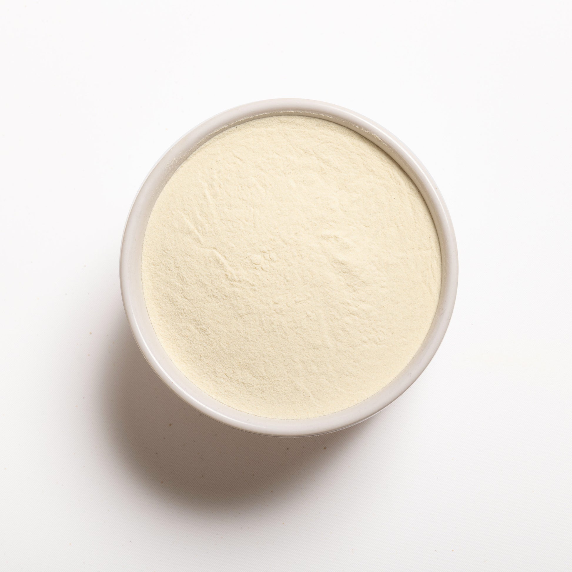 A bowl filled with potato flour on a white background.