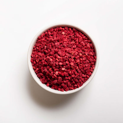 A bowl of freeze-dried raspberry granules on a white background.
