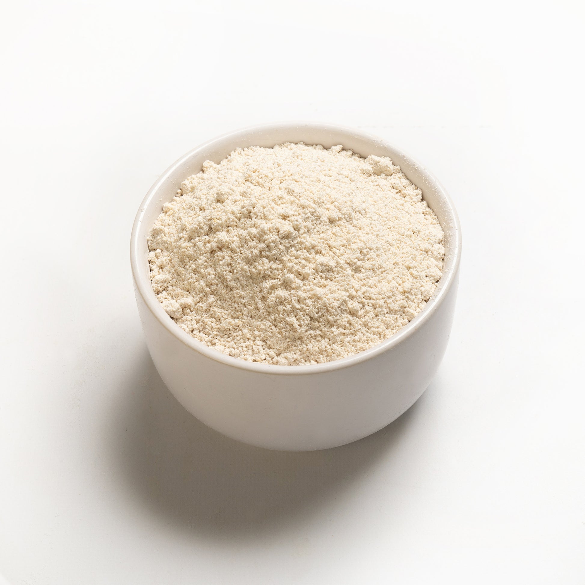 A bowl of whole oat flour on a white background.