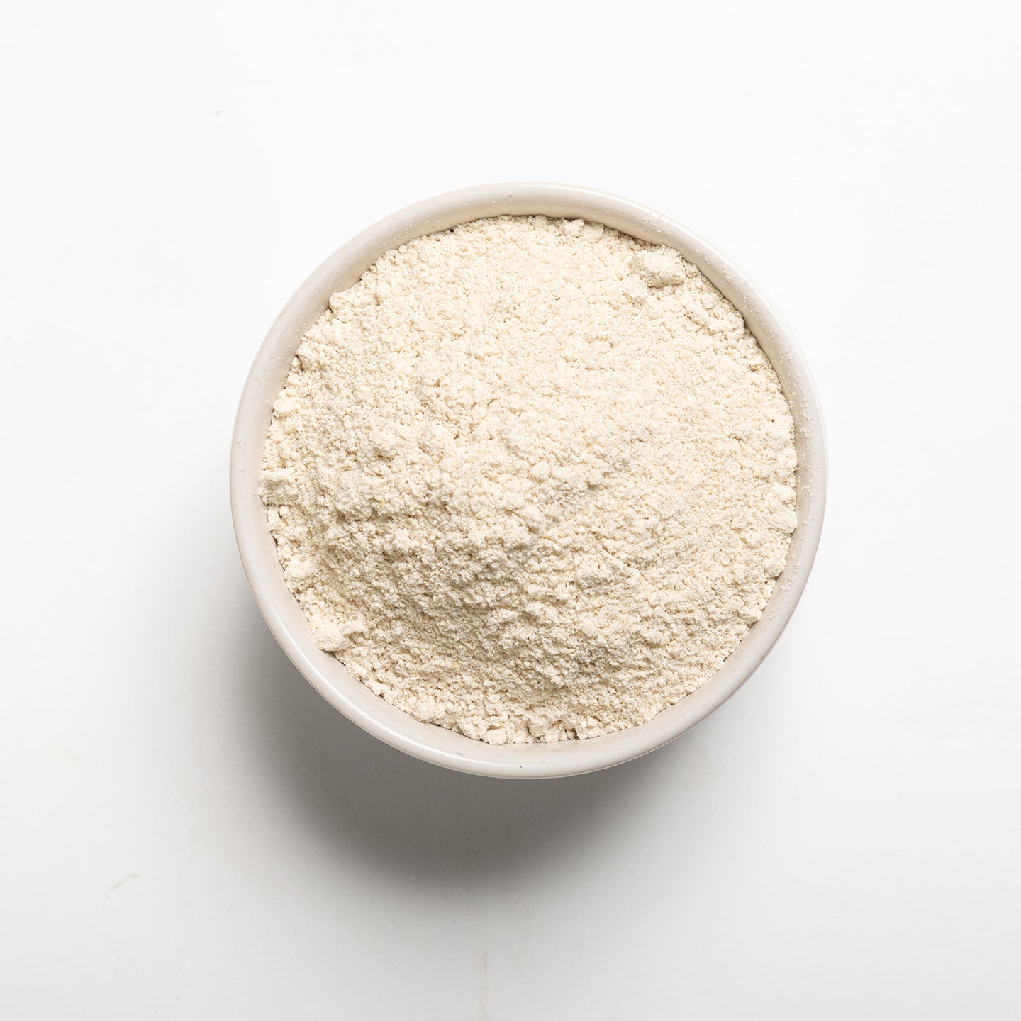 A bowl of whole oat flour on a white background.