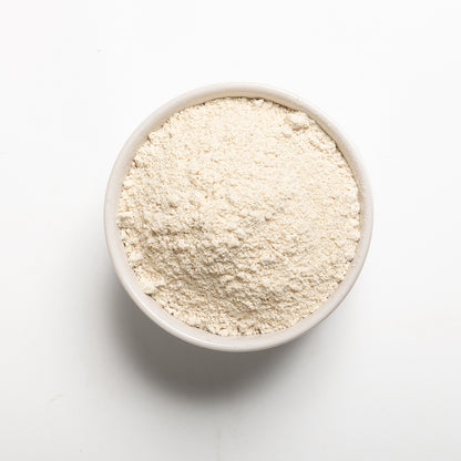 A bowl of whole oat flour on a white background.