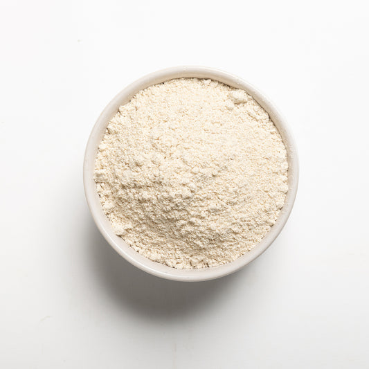A bowl of whole oat flour on a white background.