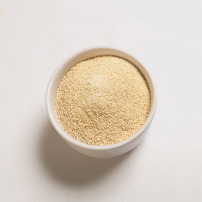 A bowl filled with granulated honey sugar on a white background.