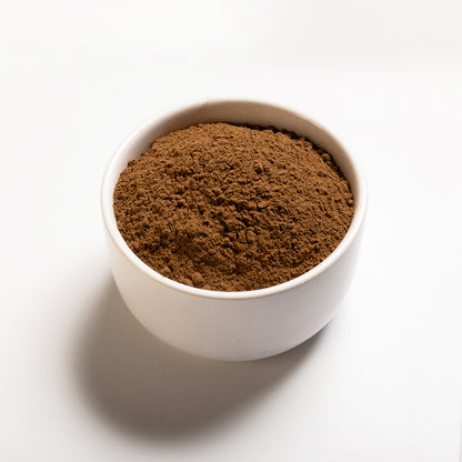 A white bowl filled with ground allspice on a white background.