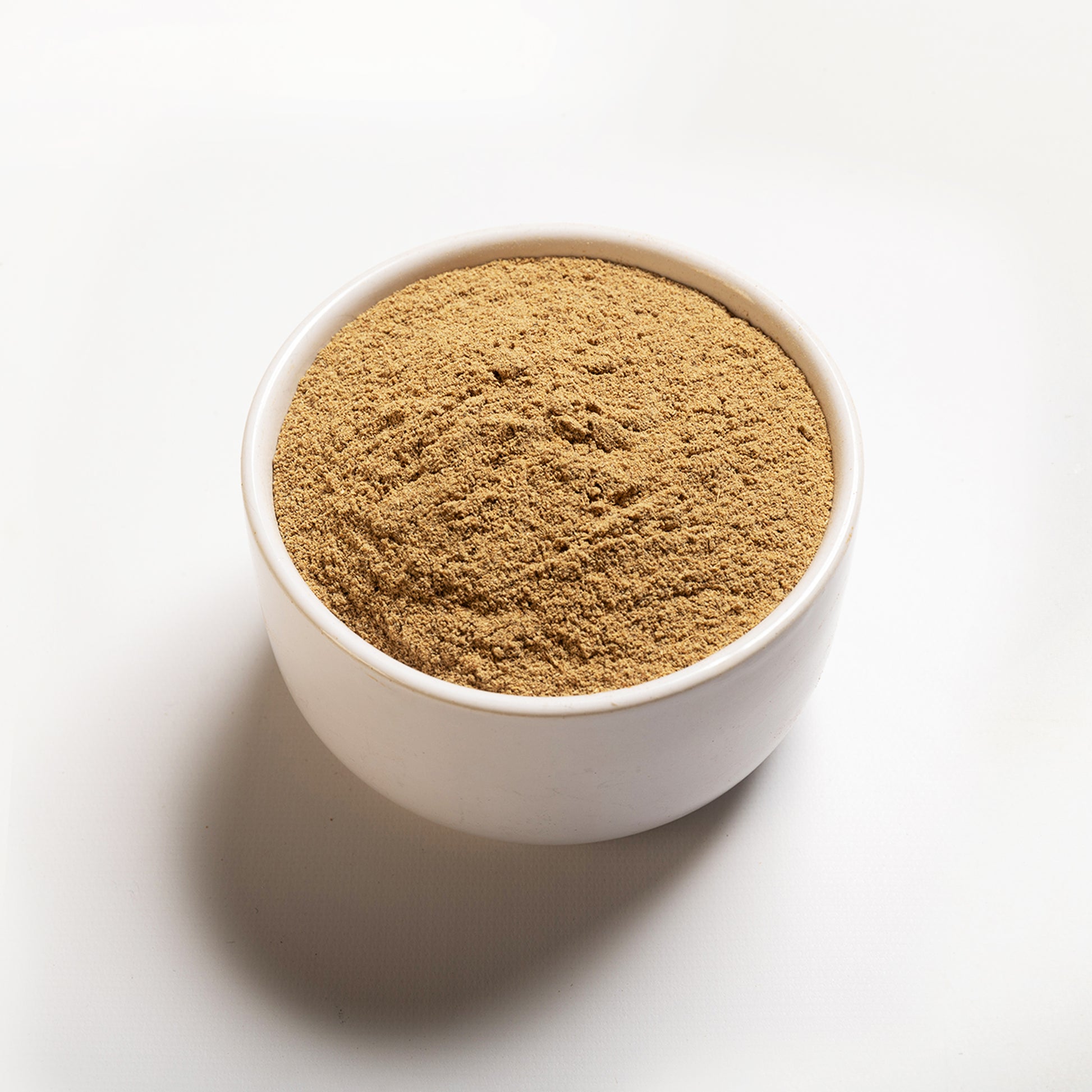 A white bowl filled with ground cardamom on a white background.