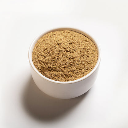 A white bowl filled with ground cardamom on a white background.
