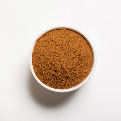 A white bowl filled with ground cinnamon spice.
