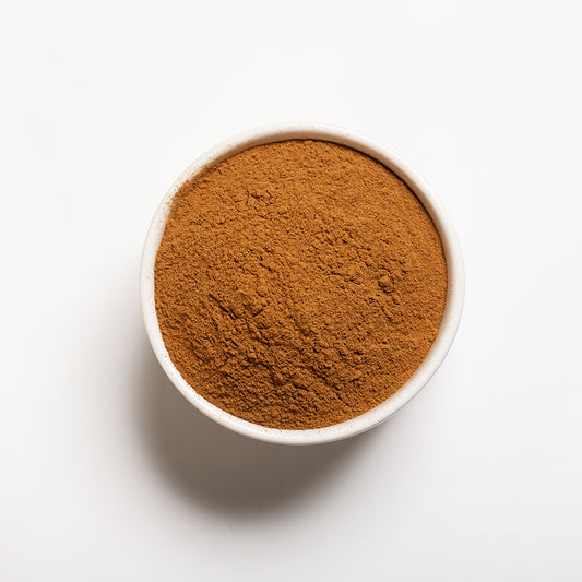 A white bowl filled with ground cinnamon spice.