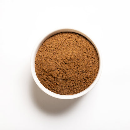 A small white bowl filled with ground cloves on a white background.