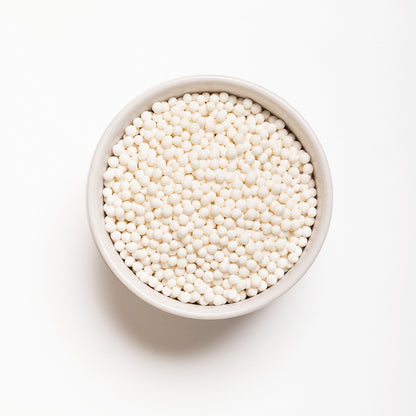 A bowl filled with white large pearl tapioca on a white background.