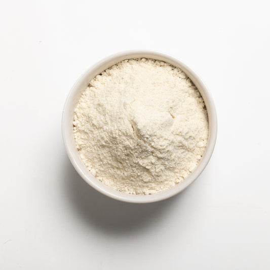 White bowl filled with brown rice flour on a light gray background