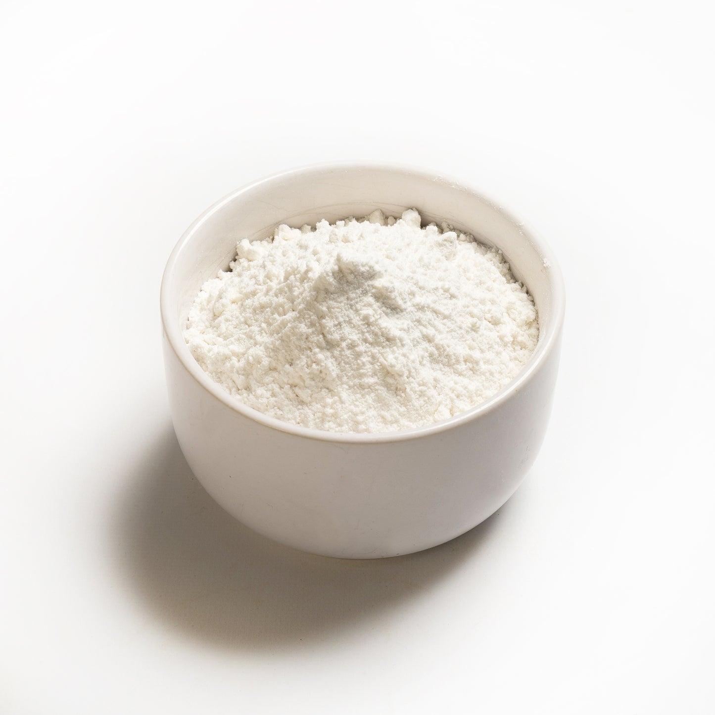 A bowl of medium grain white rice flour on a white background.
