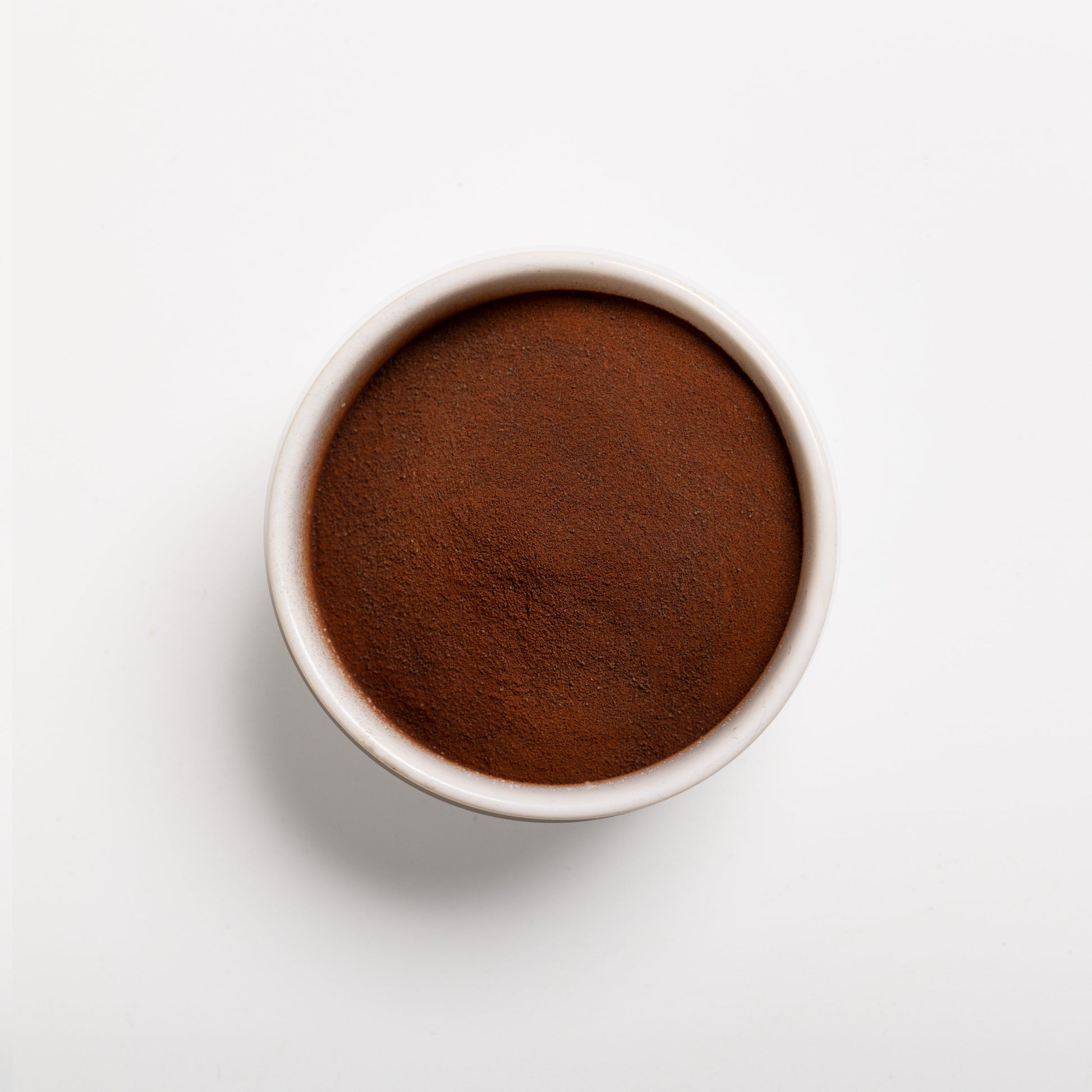 A bowl filled with natural cocoa extract powder on a white background.