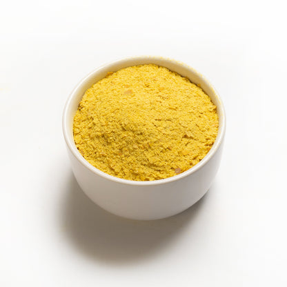 A white bowl filled with yellow nutritional yeast 