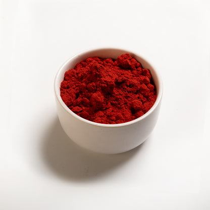 A bowl filled with Orange Vegetable Powder on a white background 