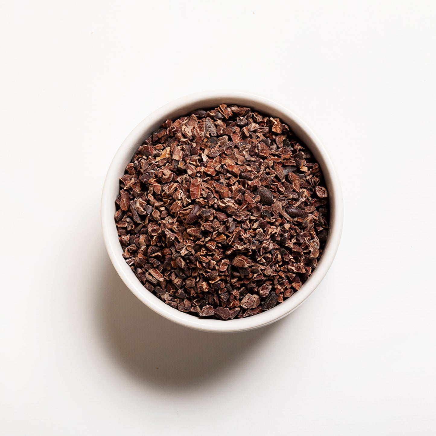 White bowl filled with organic cacao nibs 