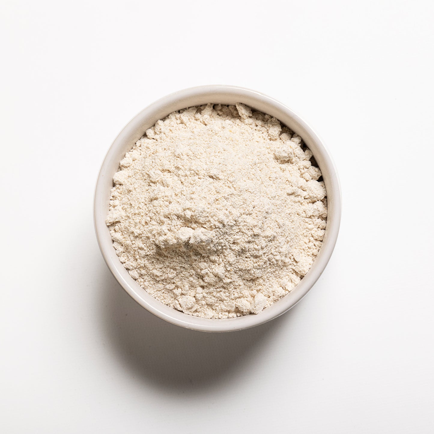 A bowl filled with organic oat flour on a white background.