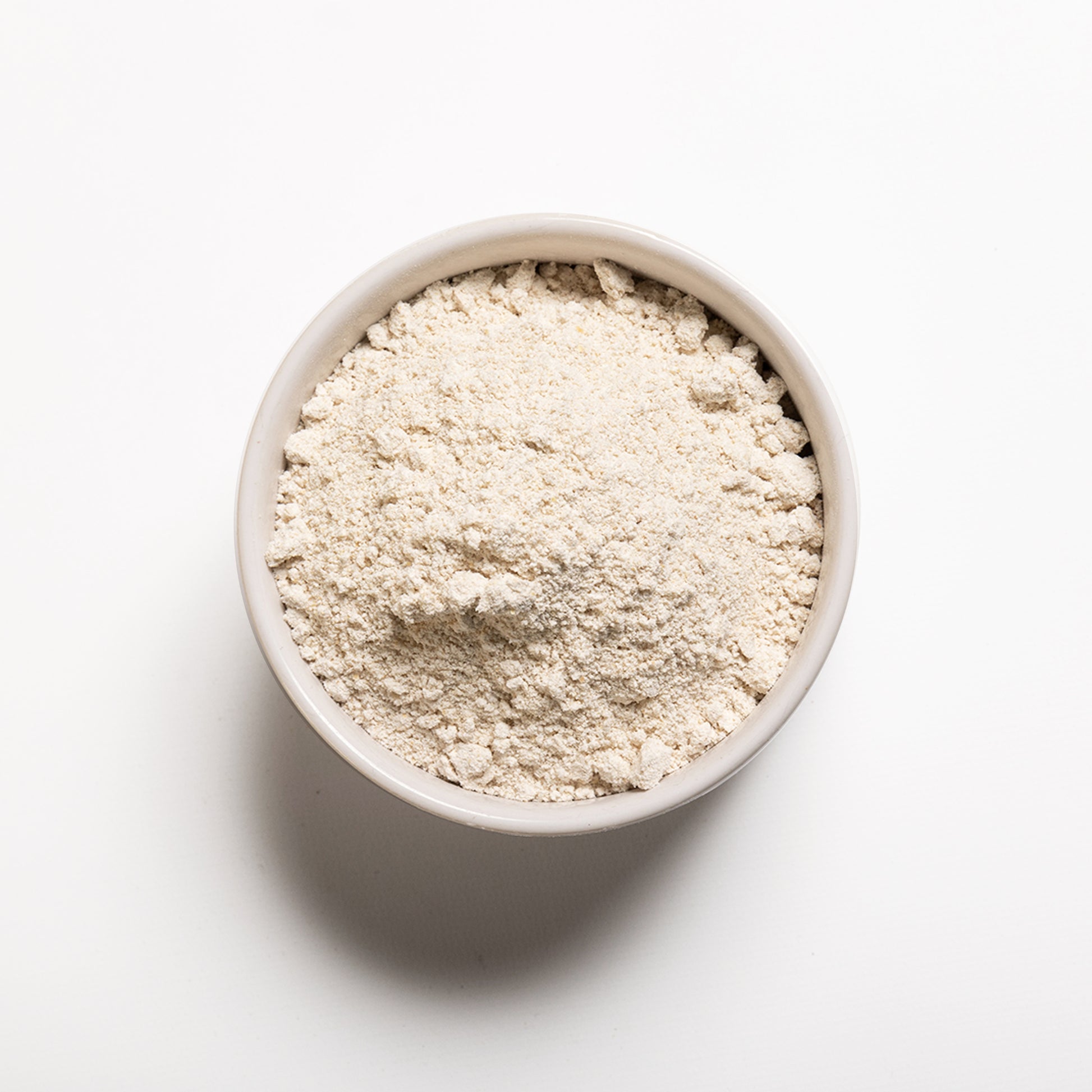 A bowl filled with organic oat flour on a white background.