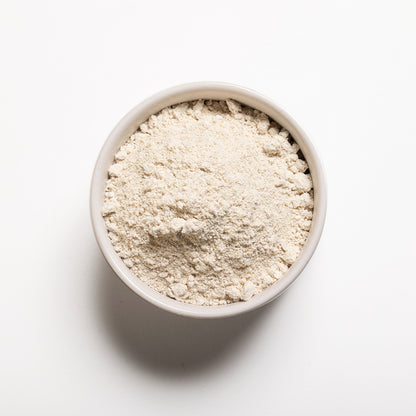 A bowl filled with organic oat flour on a white background.