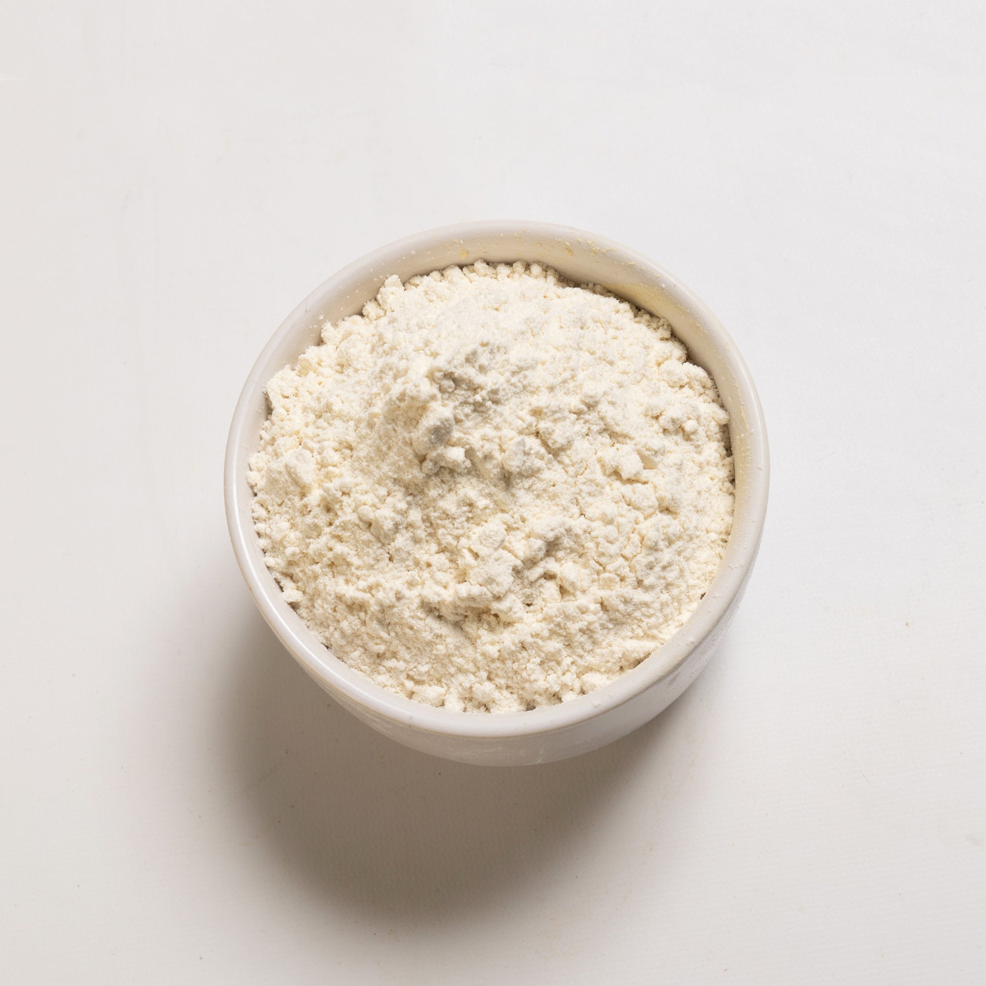 A bowl of organic bread flour on a white background.