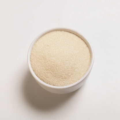 A bowl filled with organic cane sugar on a white background.