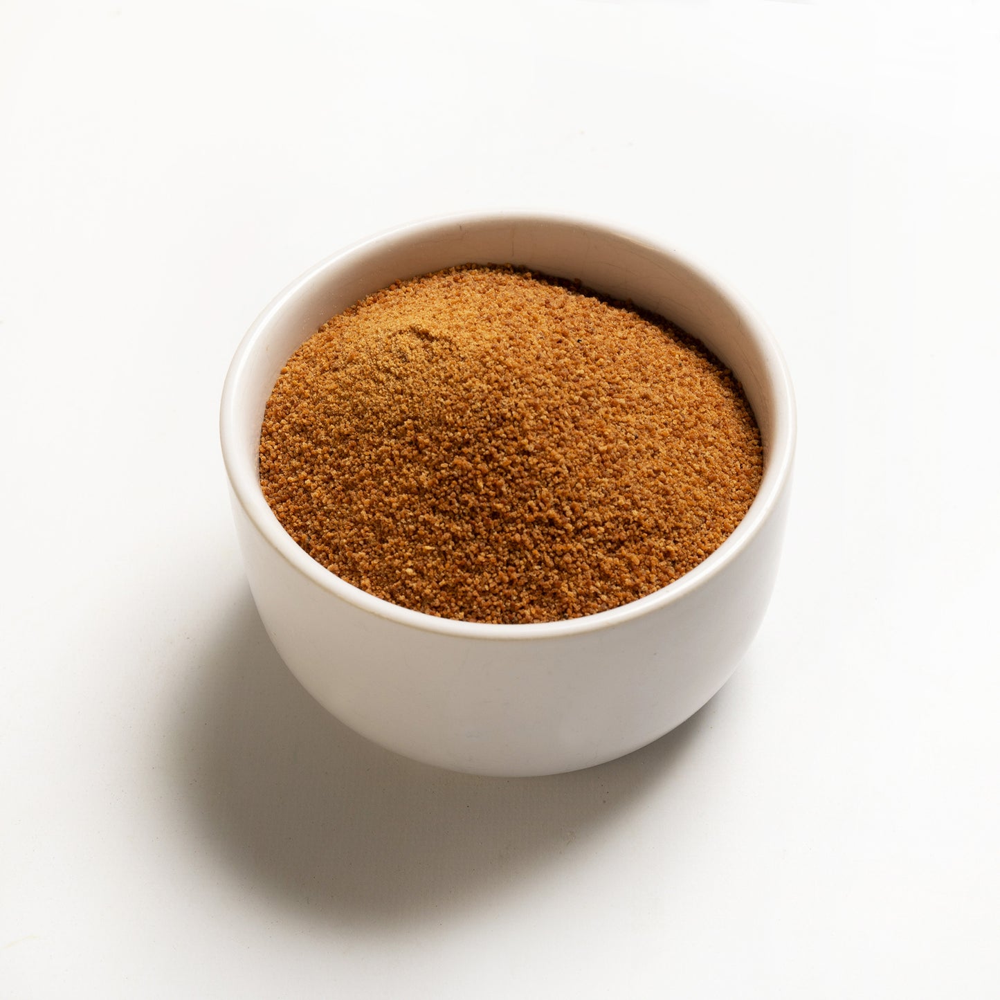 A bowl filled with organic coconut sugar on a white background.