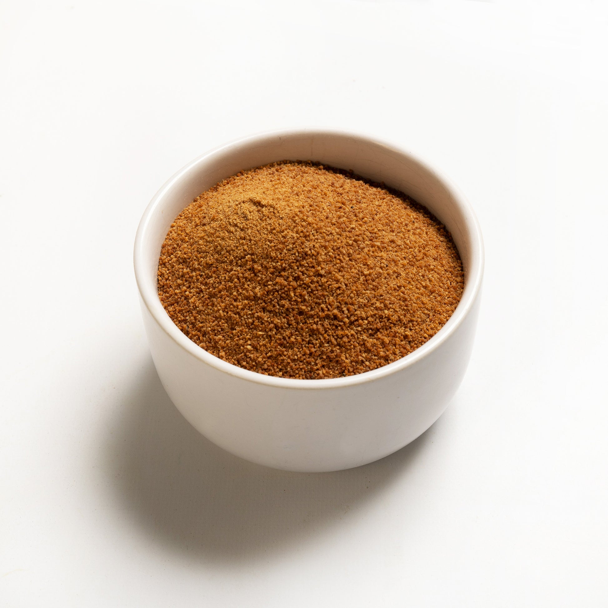 A bowl filled with organic coconut sugar on a white background.