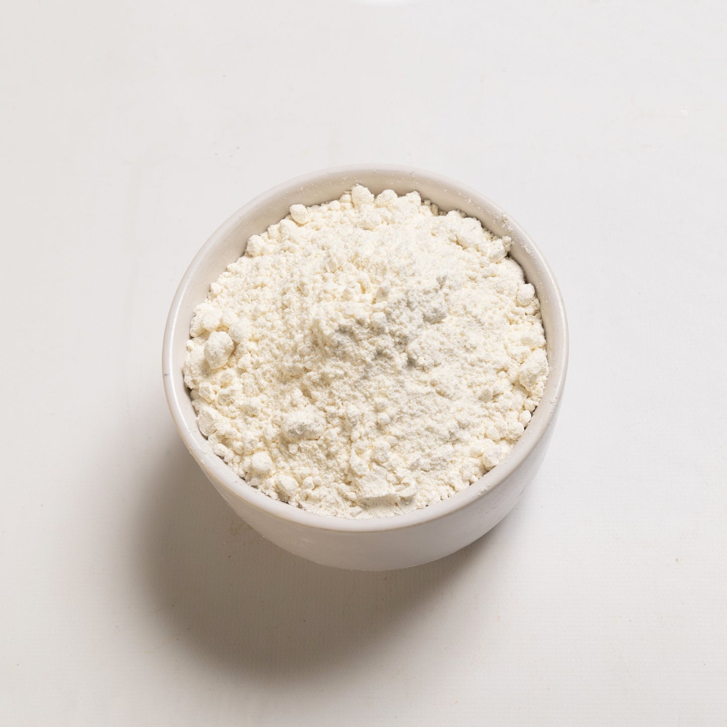 A bowl of organic pastry flour on a white background.