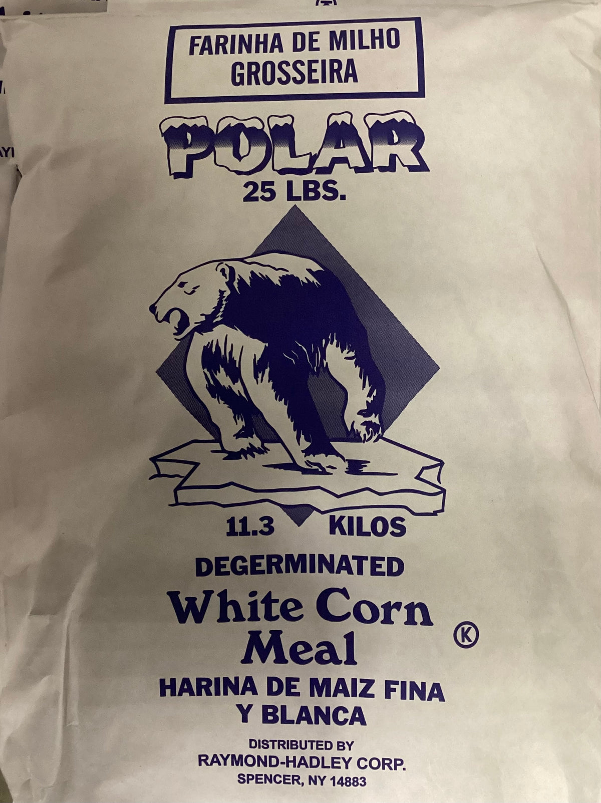 A white paper bag of Polar 25 lbs. Degerminated White Corn Meal, featuring a dark blue graphic of a polar bear on an iceberg with the brand name POLAR and product details.
