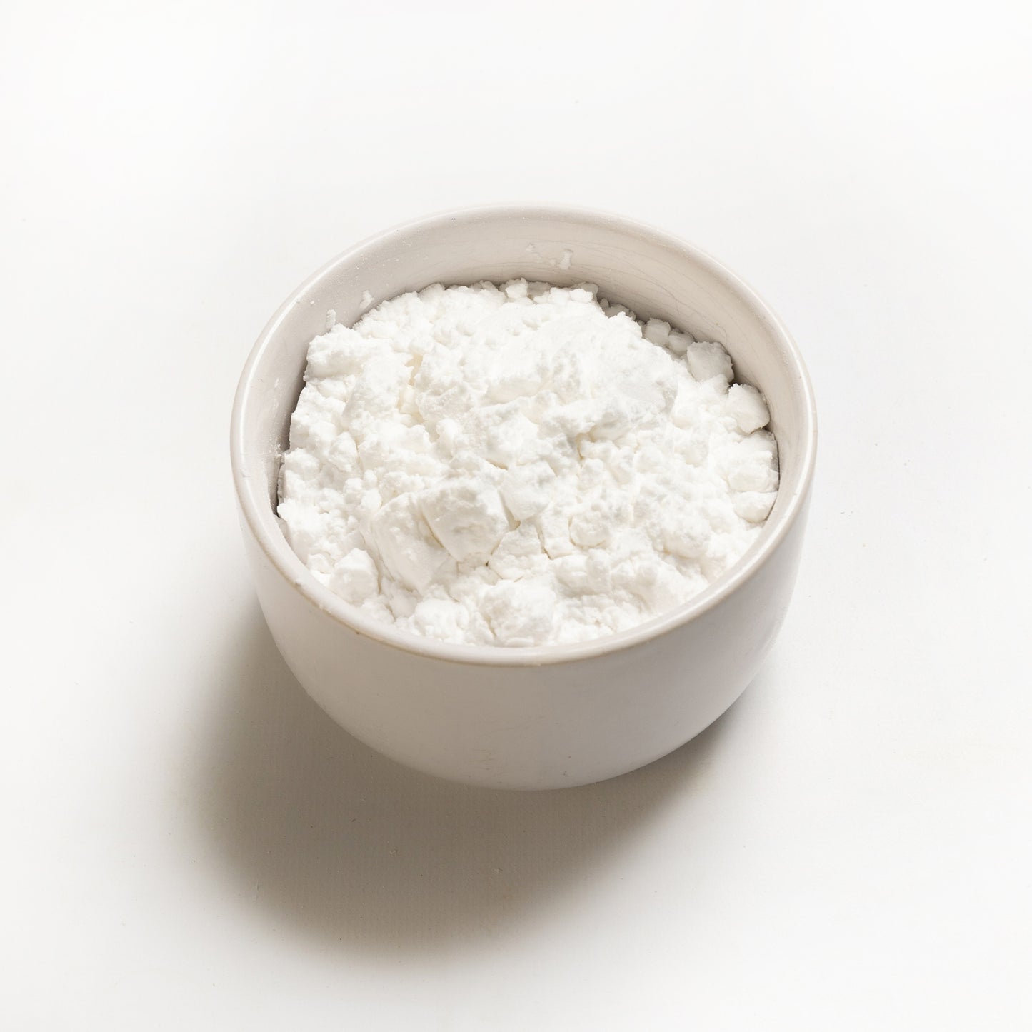 A bowl of white potato starch on a white background.