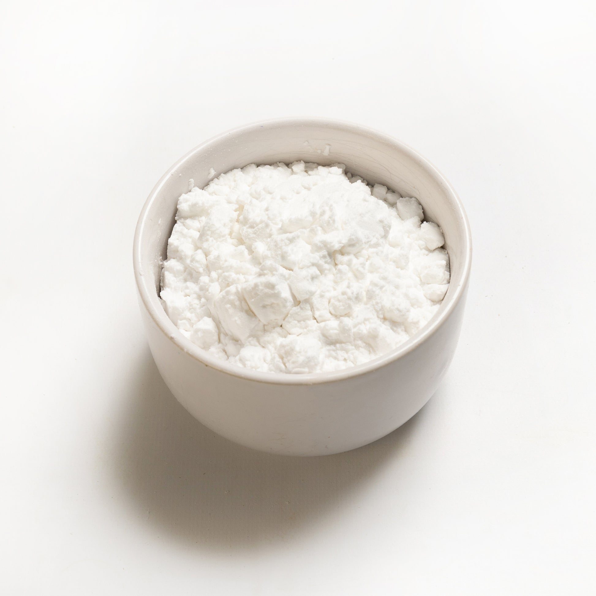A bowl of white potato starch on a white background.