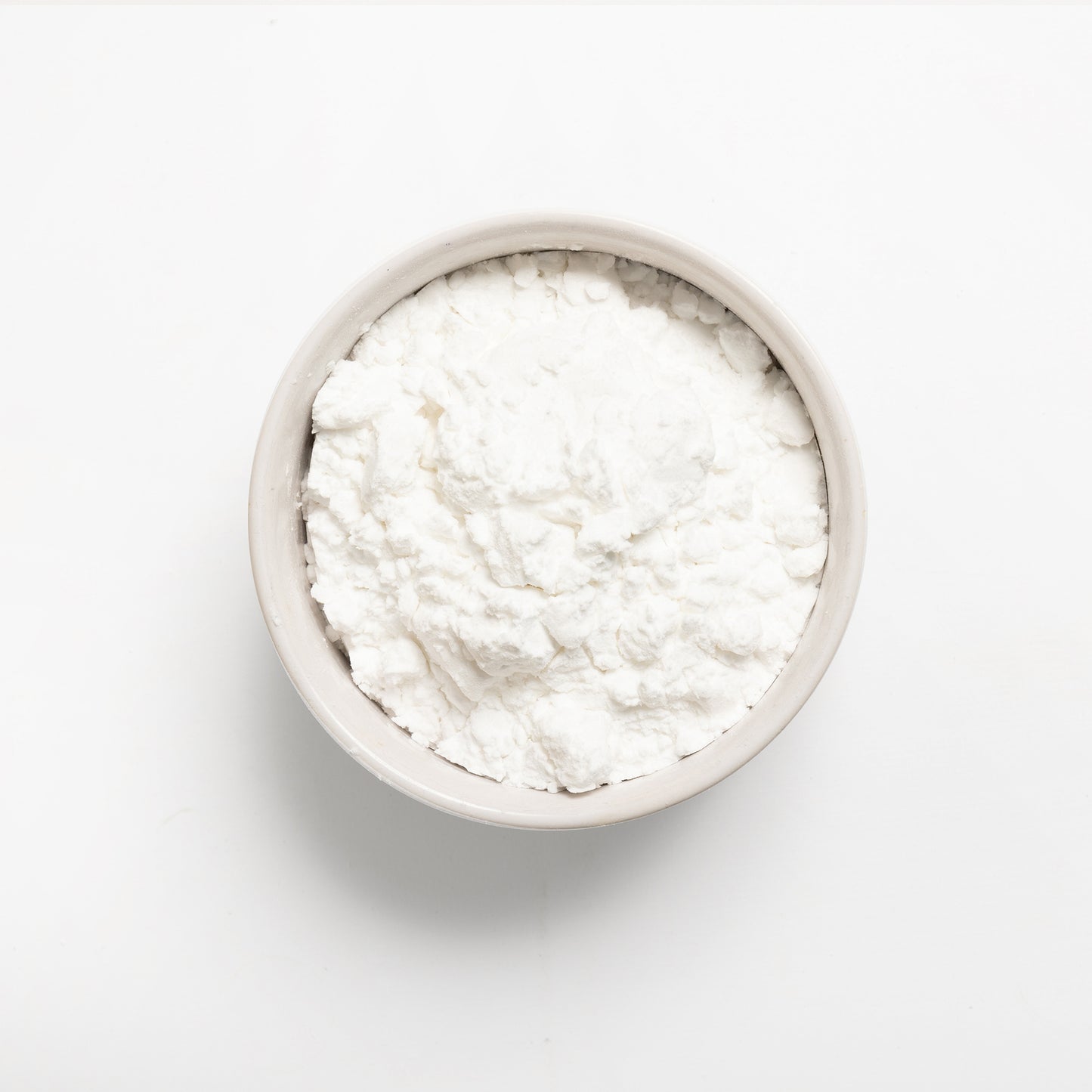 A bowl of white potato starch on a white background.